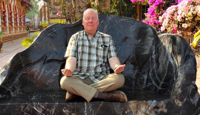 Chris Loffredo sits in a lotus pose at a Thai temple