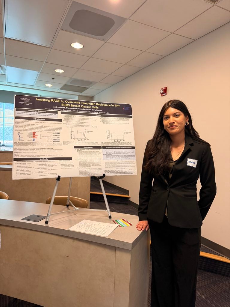 Young woman standing by a desk and a research poster in an easel