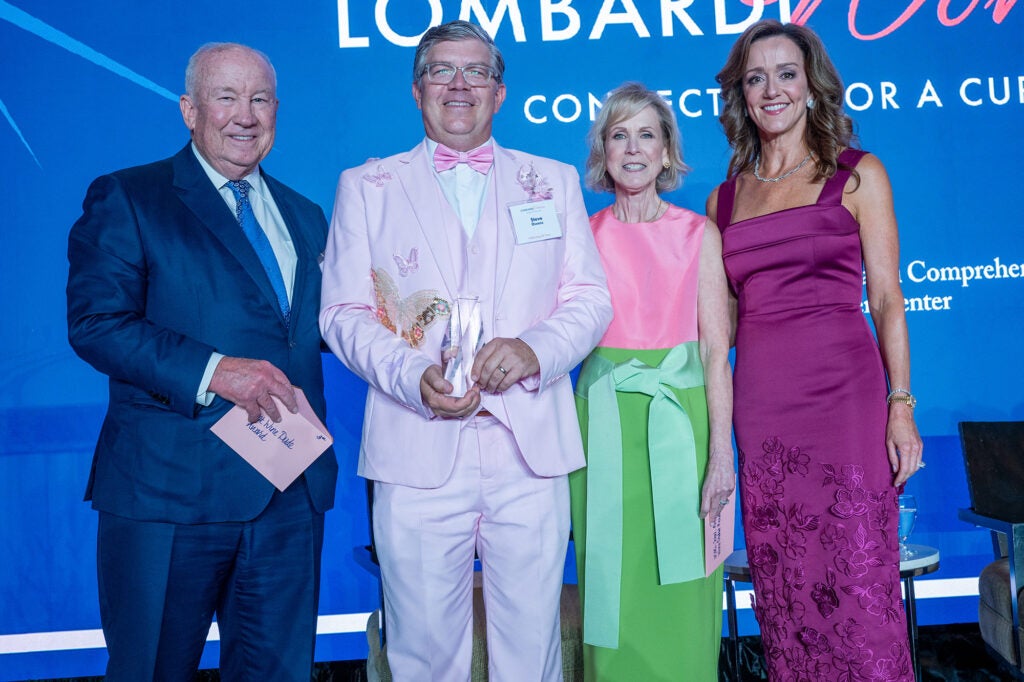 Four individuals stand together, one holding an award