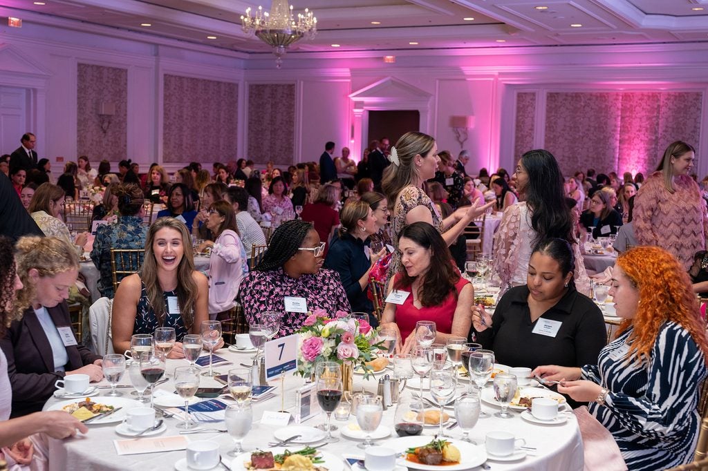 People sit at tables arranged throughout a ballroom for Lombardi Women