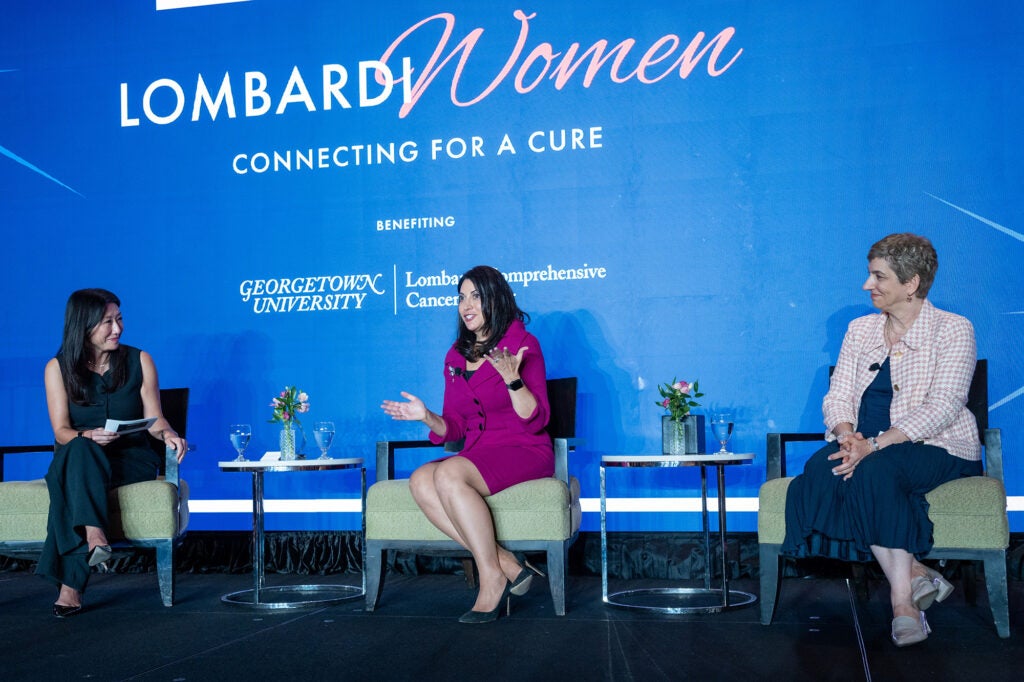 Three women have a discussion while sitting in chairs onstage